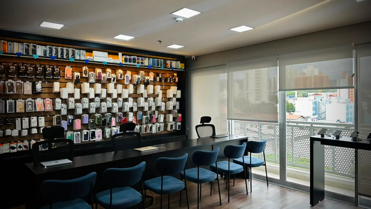 Interior da loja iTouch: parede de produtos, mesa de atendimento e janela com vista da cidade